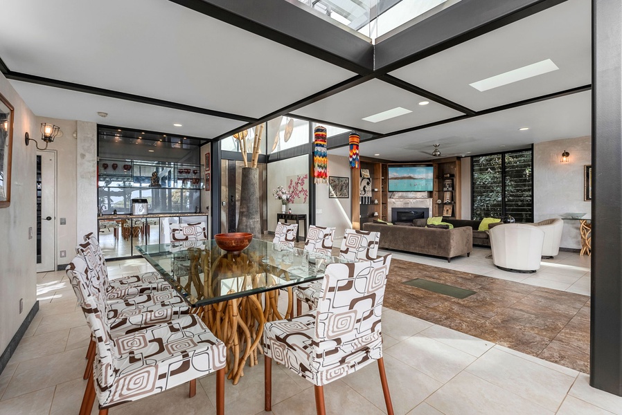 Stylish dining area with a glass-top table, modern decor, and seamless indoor-outdoor flow.