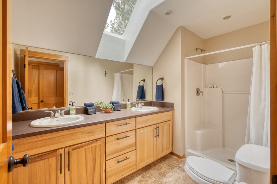 The upstairs bathroom has dual vanities, a walk-in shower and a clear roof for natural lighting