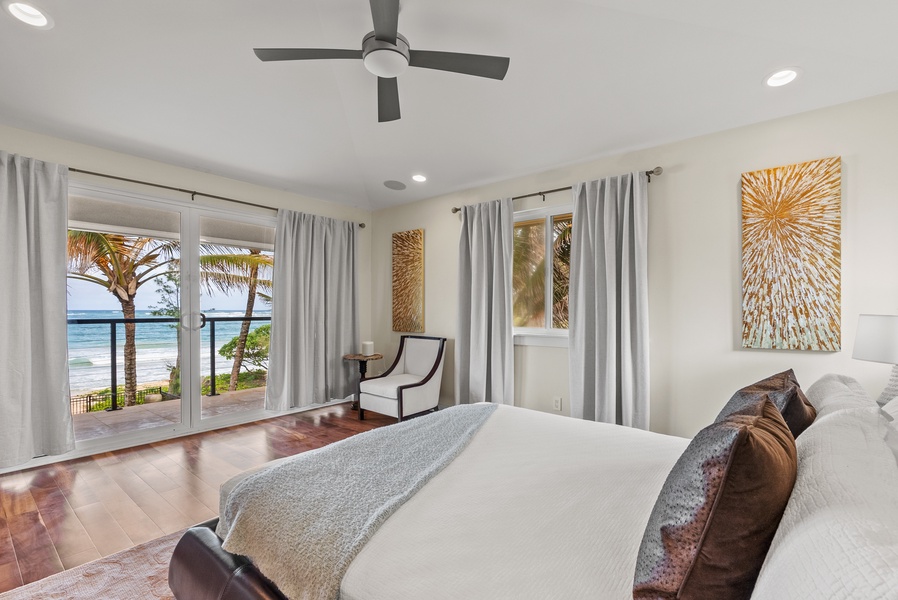 The primary suite in the upper level has large windows and ocean views.