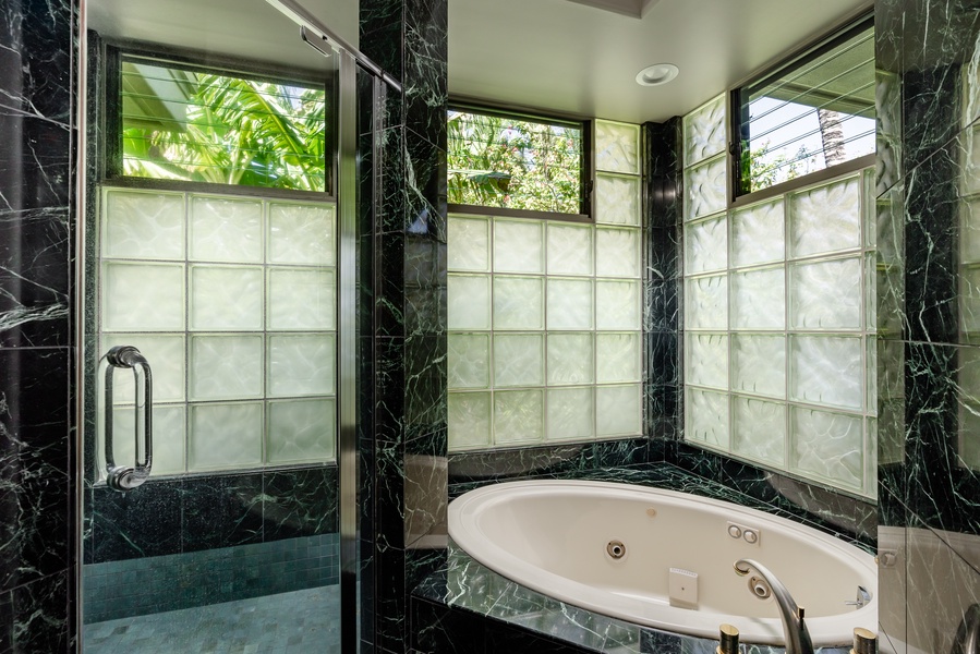 Luxurious bathroom with a jetted tub and large windows, providing a serene space to relax.