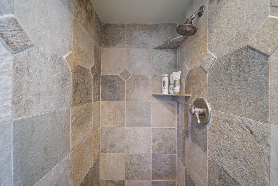 Luxurious walk-in shower with natural stone tiles and rainfall showerhead, creating a spa-like retreat in your suite.