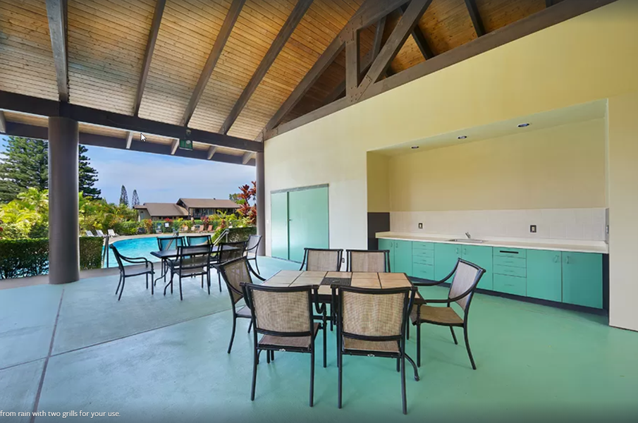 Covered dining space in pool area, with two grills for guest use