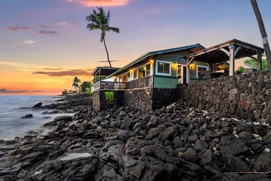 Golden hour casts a warm glow on The Cottage, perfectly set above the rocky shoreline.