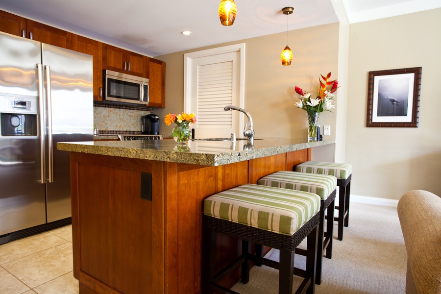 The kitchen island, with its granite countertop and comfortable bar seating, is the perfect spot for a quick breakfast or a casual chat while preparing meals.