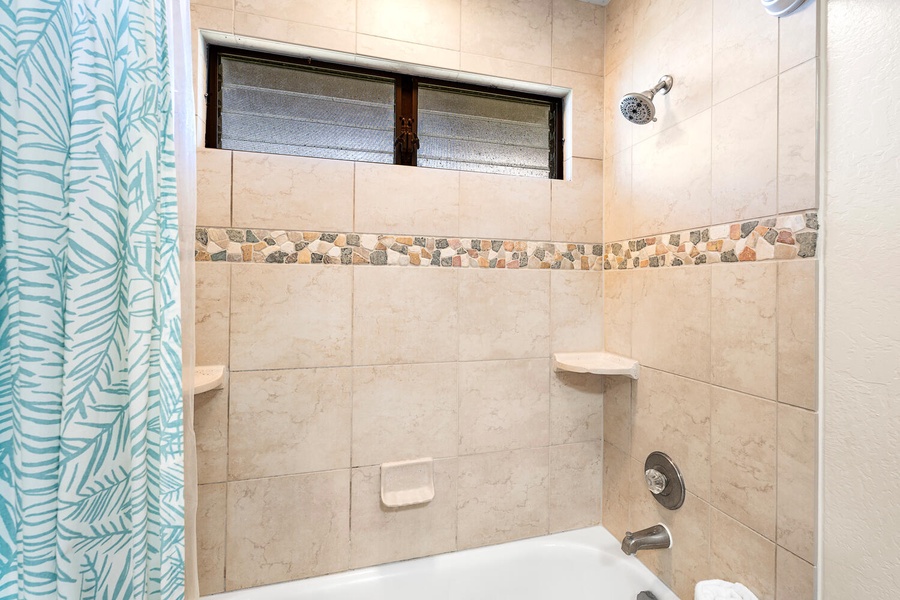 Shower and tub combo with elegant tile detail in the shared bathroom.