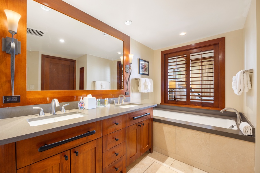 Unwind in your luxurious bathroom with rich wood cabinetry, dual vanities, and a deep soaking tub for ultimate relaxation.