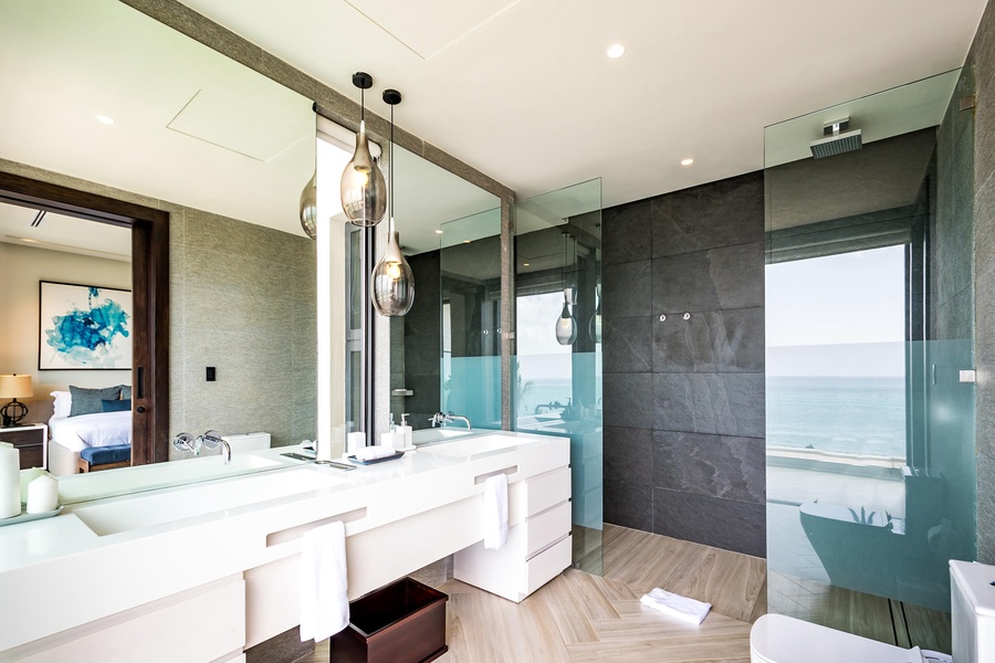 Indulge in the modern ensuite bathroom with a dual vanity, glass-enclosed shower, and breathtaking ocean views.