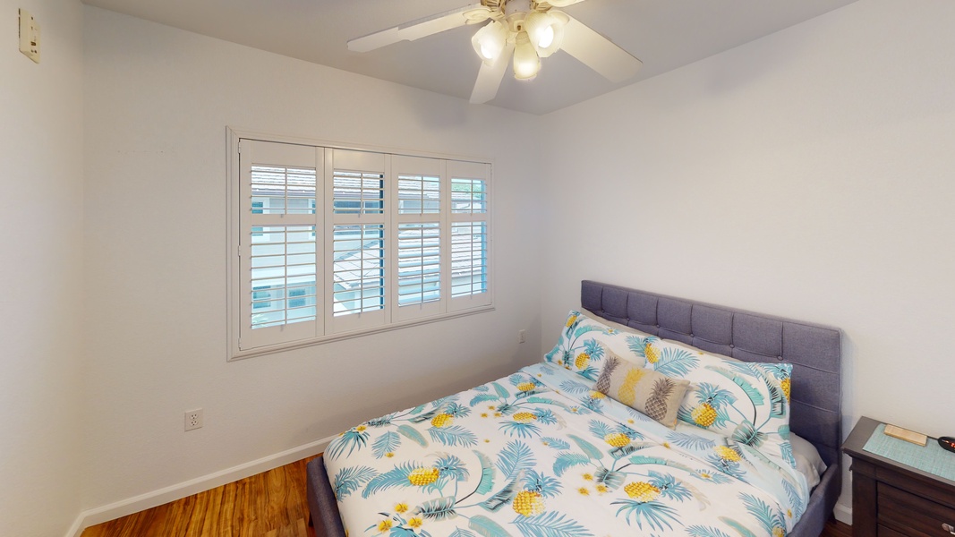 The second guest bedroom with natural light, a ceiling fan and pops of color on the soft bedding.