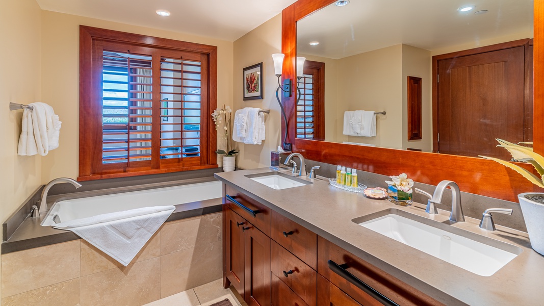 The primary guest bathroom has a double vanity and luxurious soaking tub.
