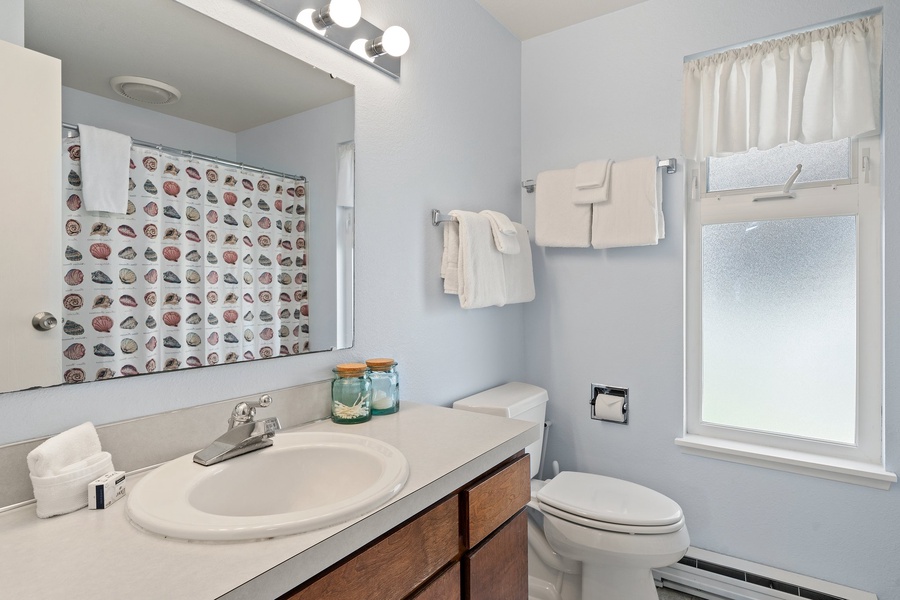 The guest bathroom is light and has storage and tub/shower combo.