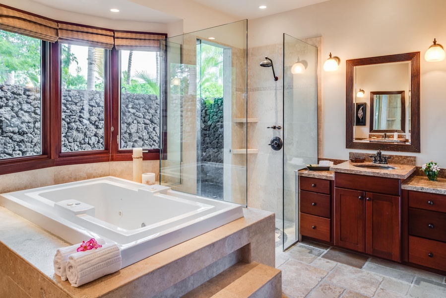 The Jacuzzi tub is adjacent to the glass enclosed walk-in shower.