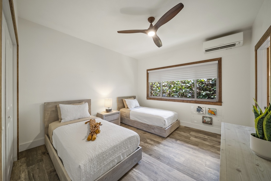 Twin guest bedroom with garden views, ceiling fan, and natural light—great for kids or friends.