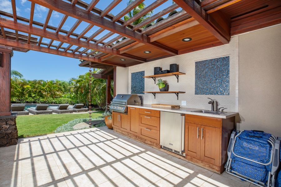 Outdoor kitchen equipped with a built-in grill, refrigerator, and ample counter space, perfect for cooking and entertaining in the open air.