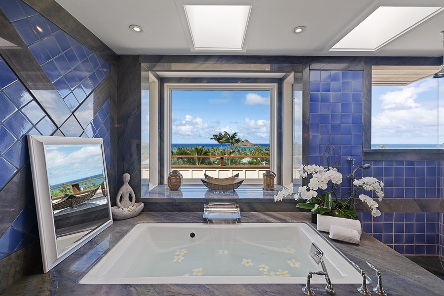 The spa-like ensuite bathroom offers a large soaking tub, featuring outdoor views.