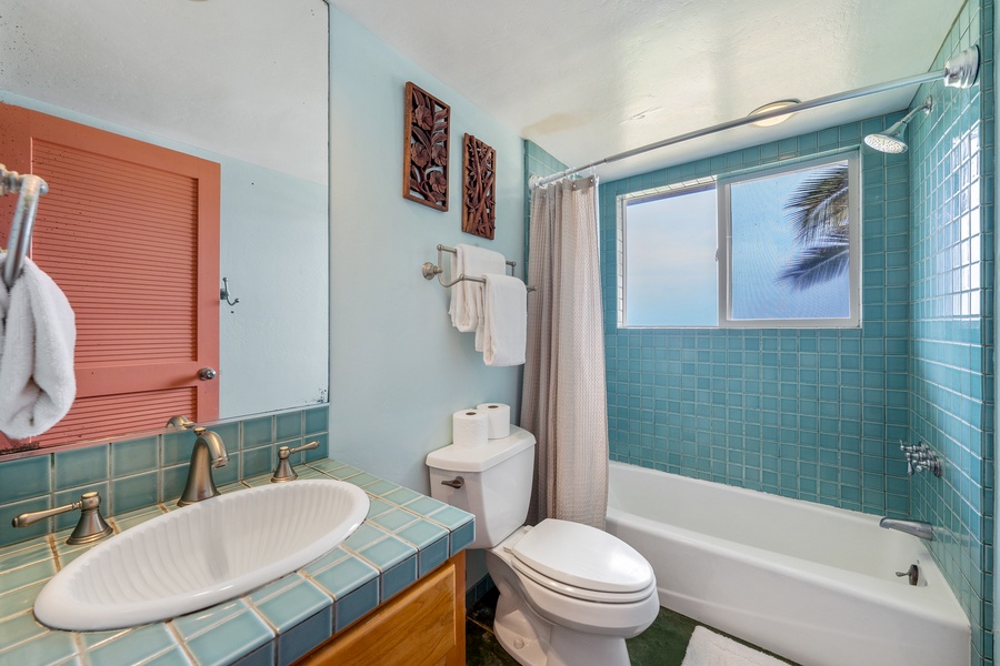 Refresh in your turquoise-tiled bathroom with tropical palm views and thoughtful touches like plush towels and decorative artwork.
