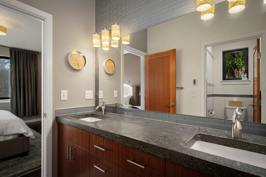Sleek double vanity with warm wood cabinetry and modern pendant lighting.