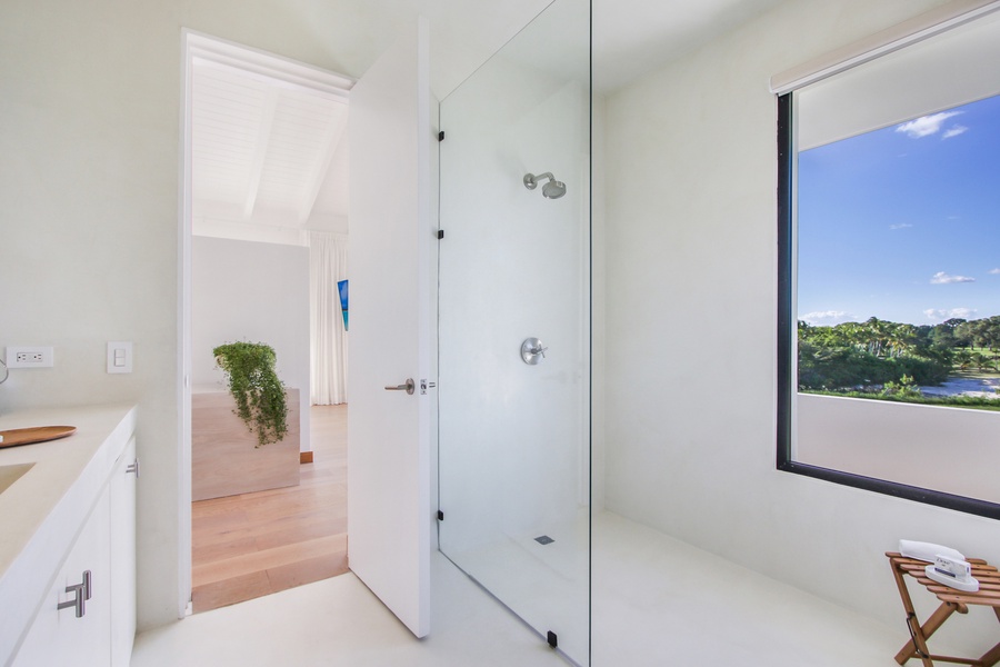 Spacious ensuite bathroom with a large glass shower and serene views.
