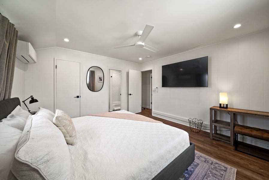 Cozy sleeping area highlighted by neutral tones, ceiling fan, and easy flow into the living space.