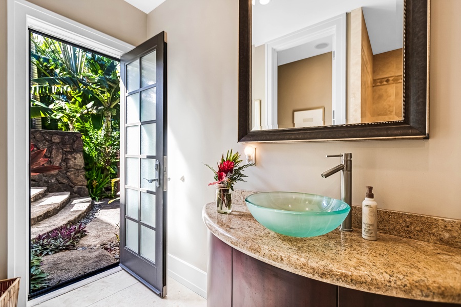 Outdoor-access bathroom with a green glass vessel sink.