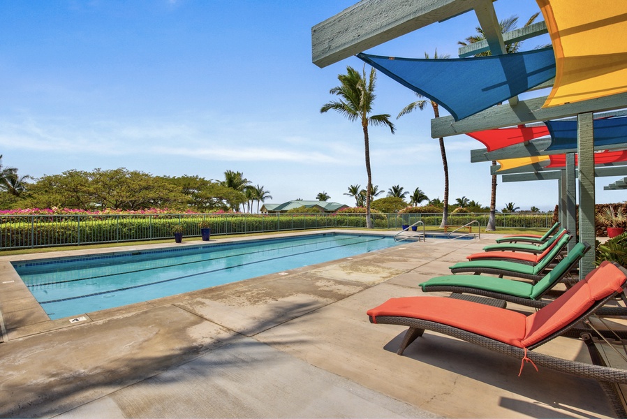 Alternate view of amenities center pool with colorful loungers and shade sails.