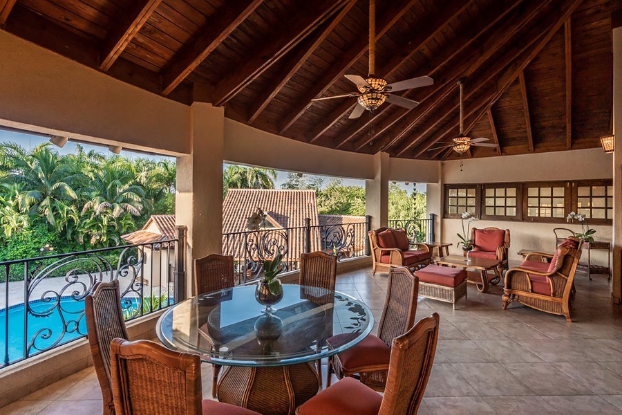 Unwind in the private patio, with comfortable seating and ceiling fans, overlooking the pool and gardens.