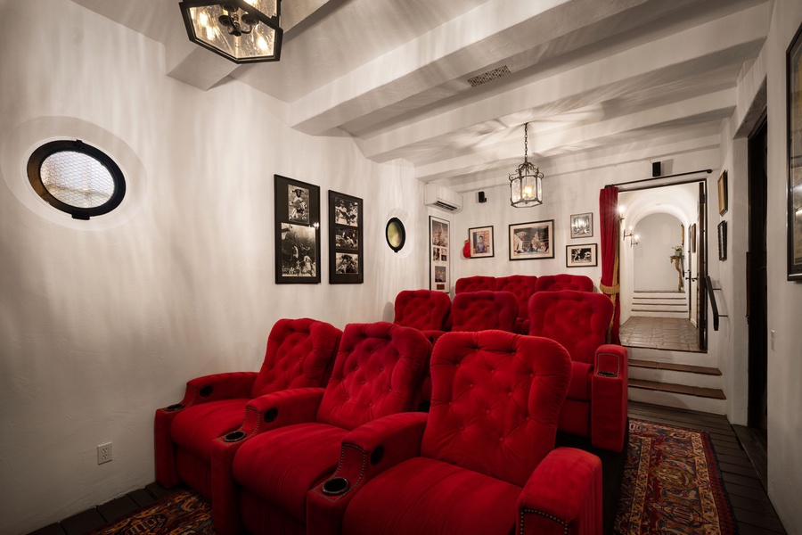 Sink into plush red theater seats for your private movie nights in this elegant home cinema with vintage charm and modern comfort.