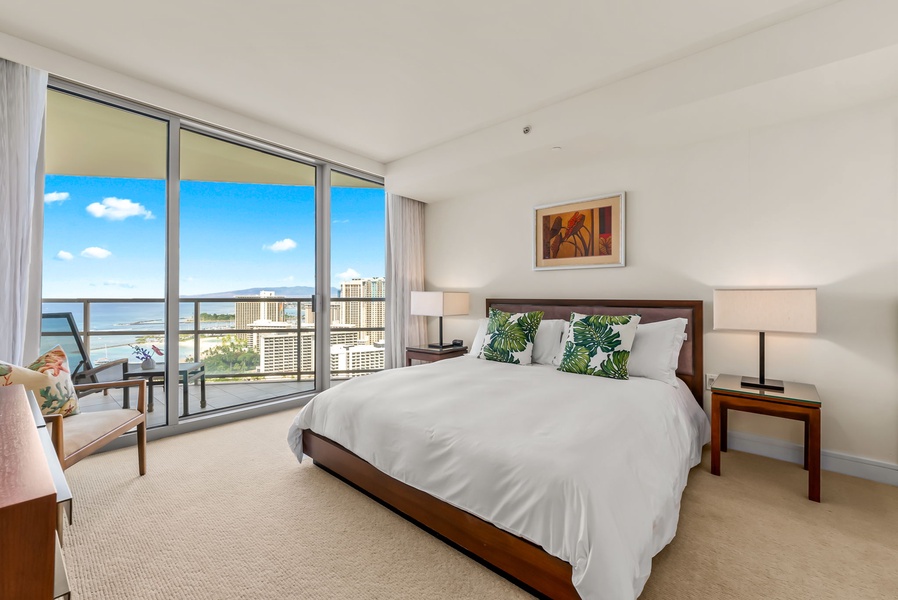 Guest bedroom with floor-to-ceiling windows offering stunning views and direct access to a private lanai.