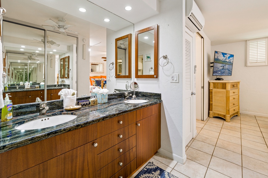 This spacious bathroom features a double vanity with sleek granite countertops, plenty of storage, and modern lighting