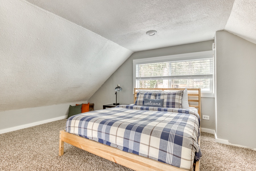 Guest bedroom three, located in the loft area above the common room, has a queen bed