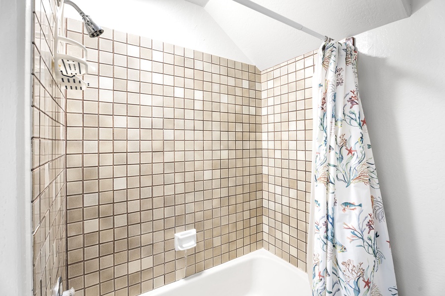 Refresh in your bright, tiled shower with thoughtful amenities and charming botanical curtain details.