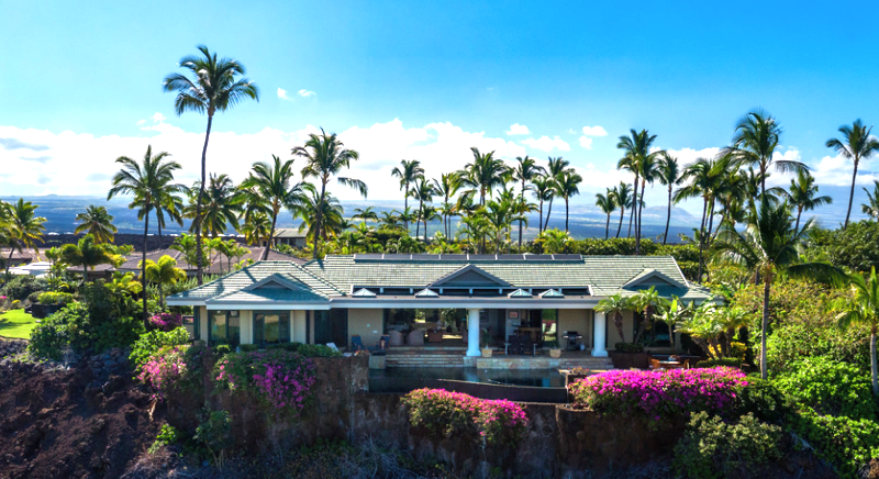 Charming tropical home with a well-maintained exterior, surrounded by lush greenery and palm trees.