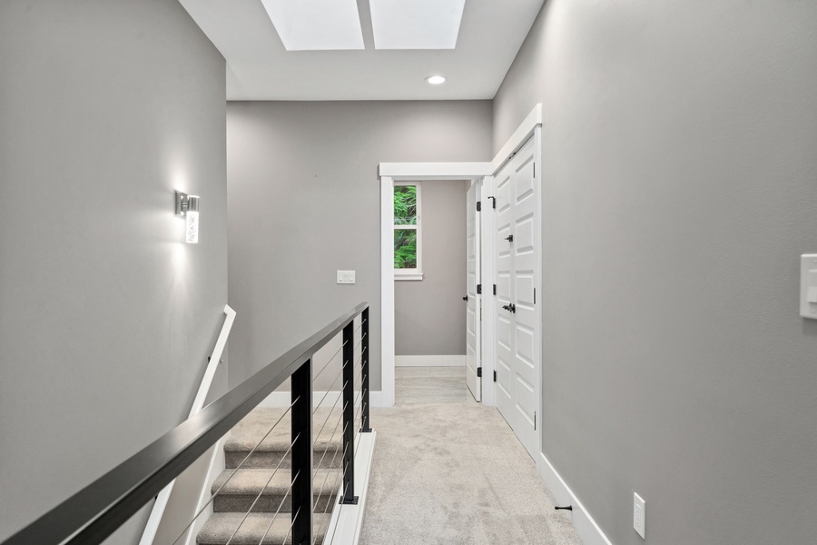 Step into this bright, modern hallway where natural light floods through the skylight above, creating a welcoming atmosphere for your stay.