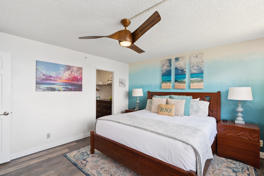Royal Kahana 308’s airy bedroom showcases serene ocean art, soft lighting, and plush bedding for restful nights.