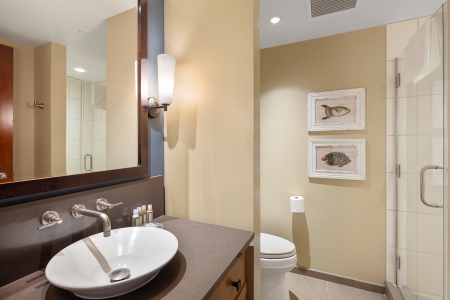 Your private bathroom features elegant vessel sink, walk-in shower, and coastal-inspired artwork for peaceful morning routines.