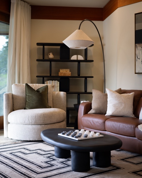 Sink into plush seating where warm wood beams and soft lighting create your perfect reading corner with thoughtful shelving nearby.