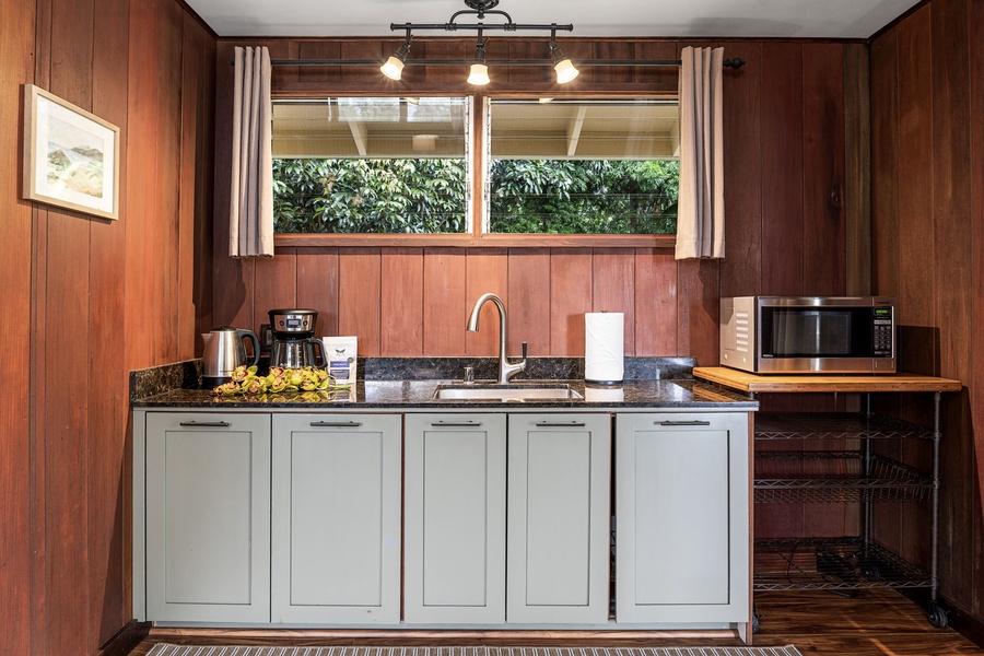 Your kitchenette blends vintage charm with modern conveniences—brew coffee, prepare light meals, and enjoy lush garden views through the sunlit windows above the sink.