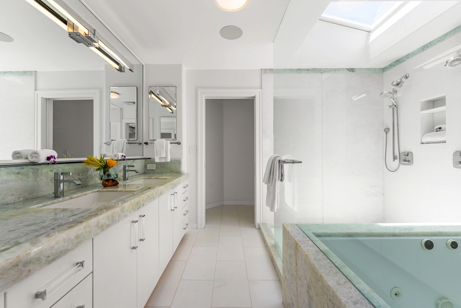 Spa-inspired primary ensuite with dual vanities, a soaking tub, and an ocean-facing walk-in shower.