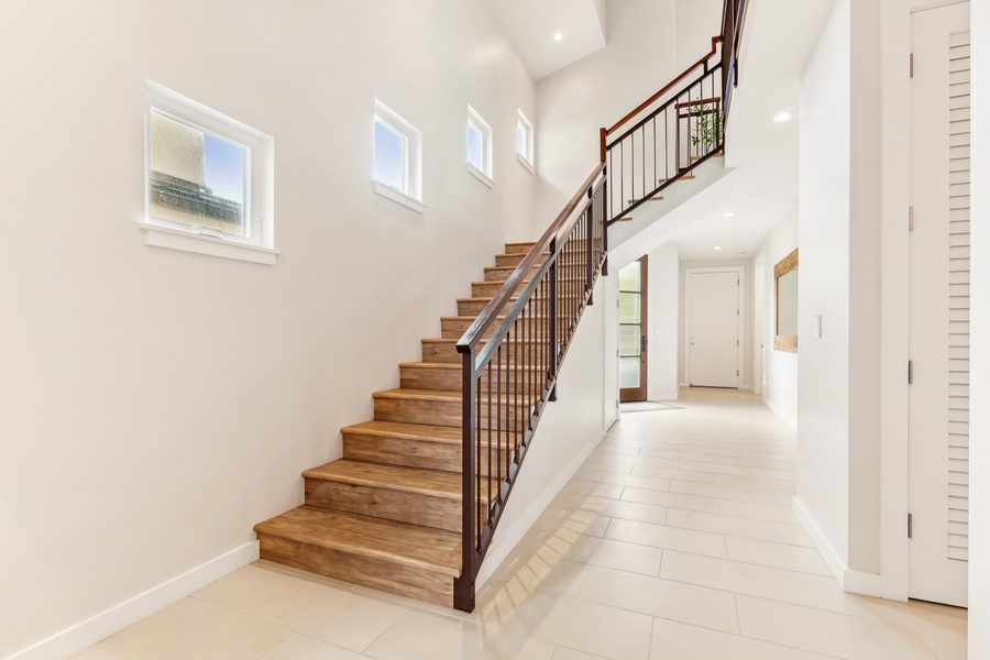 Wide staircase with sleek wooden steps and modern railings leading to upper levels.