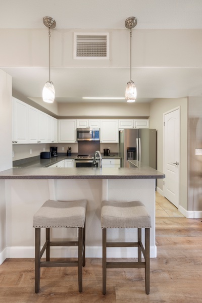 Barstool seating and pendant lighting create a versatile kitchen space—equally ideal for meal prep, laptop time, or morning mimosas.