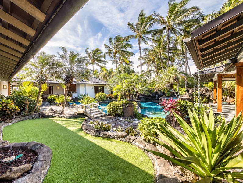 Lush landscaping and lava rock accents frame the tropical pool and garden pathways.