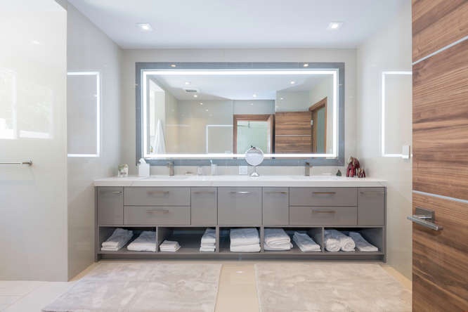Spacious guest bathroom with dual sinks, backlit mirrors, and plenty of room for two.