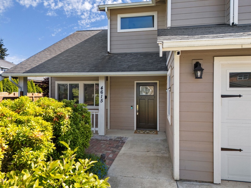 A welcoming facade featuring a covered entryway with decorative address numbers, flanked by vibrant landscaping and a private garage, setting the scene for your arrival.