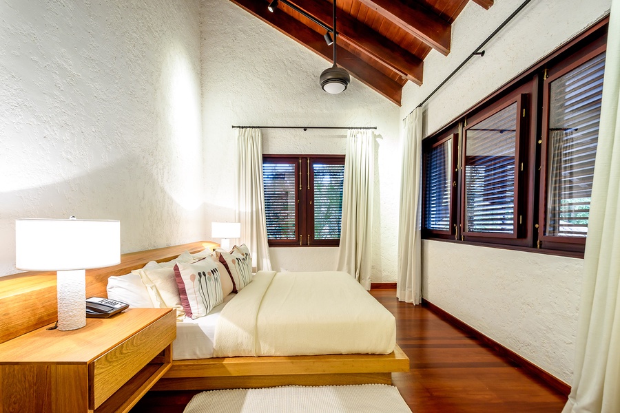 Experience a restful night in the guest bedroom with natural light and a wooden bed frame.