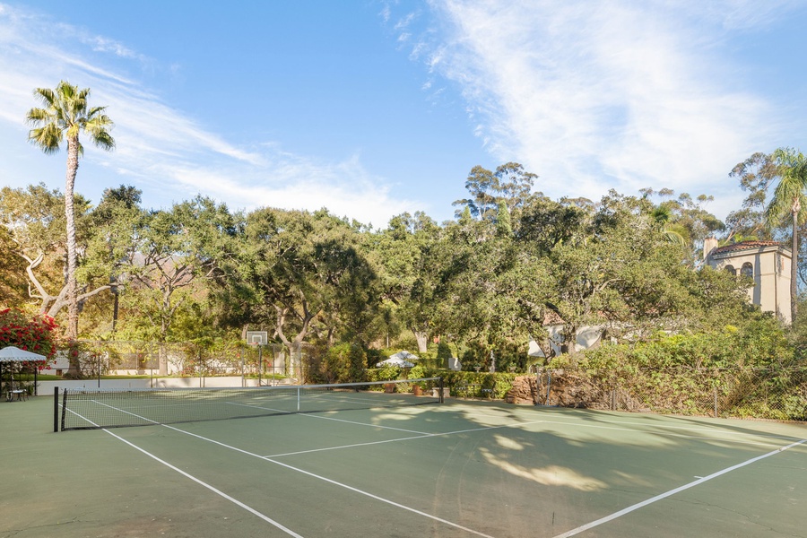 Private tennis court surrounded by lush trees and palm trees, perfect for an active getaway in a serene natural setting.