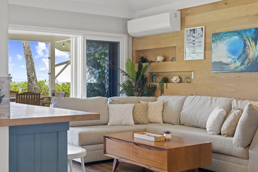 Step into the bright, beachy lower-level living area, complete with a plush sofa, a flat-screen TV, and pocket doors framing exquisite views—your warm welcome to our beachfront home.