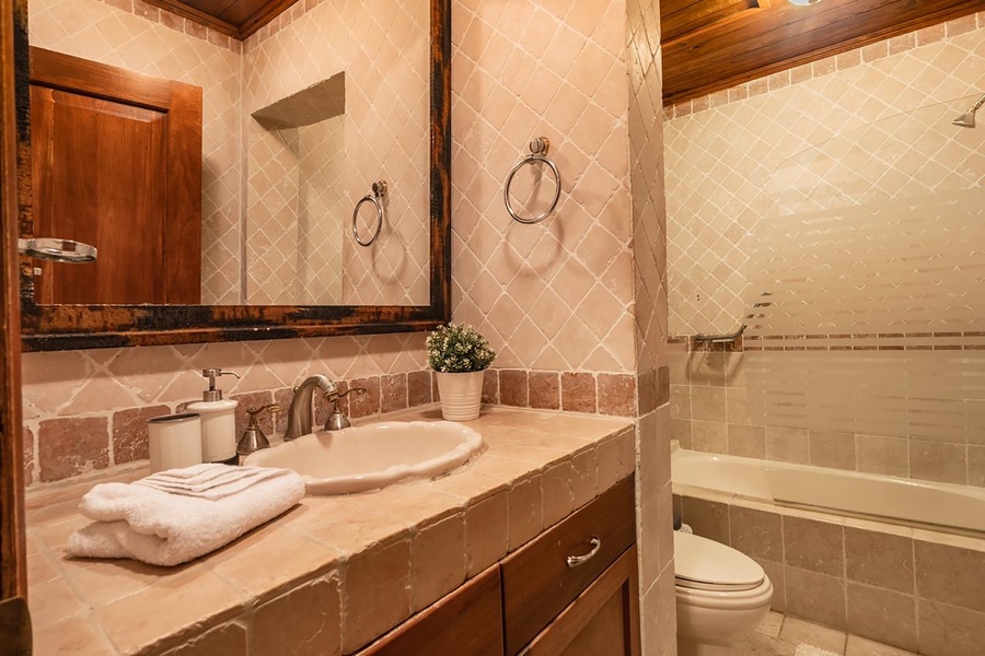 Elegant ensuite bath with tiled walls and a spacious vanity area.