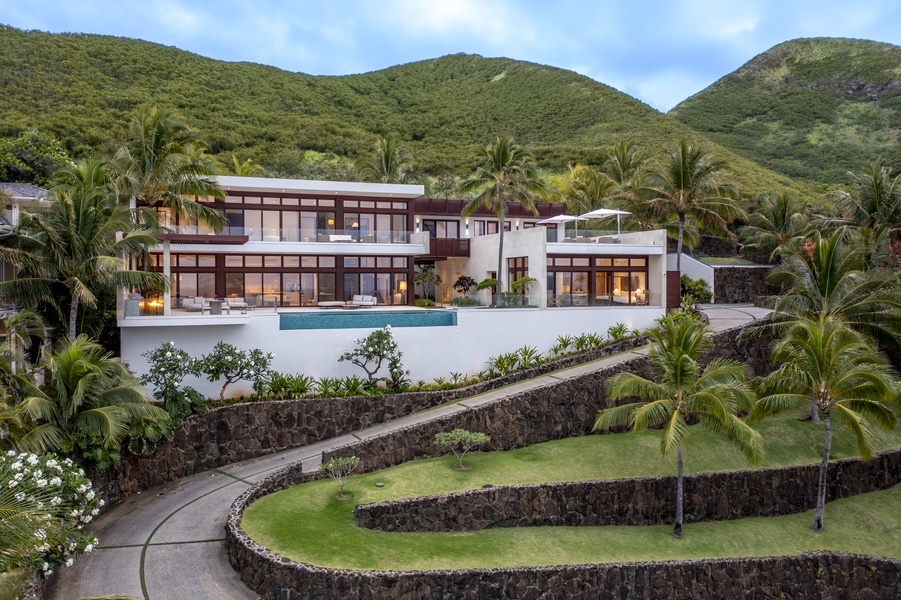 Driveway to the estate surrounded by lush greenery, setting the tone for a luxurious stay.