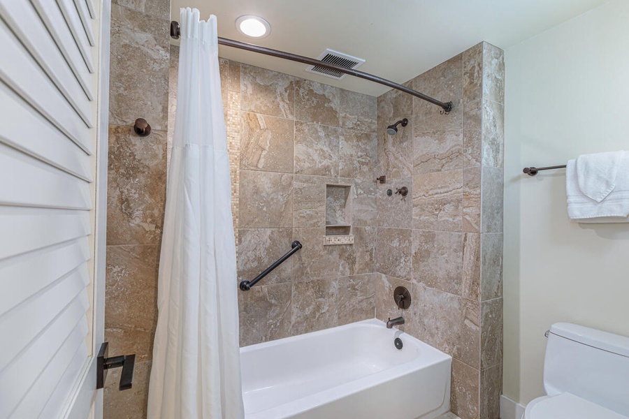 Freshen up after the beach in this tiled bathroom with a tub and shower combo.