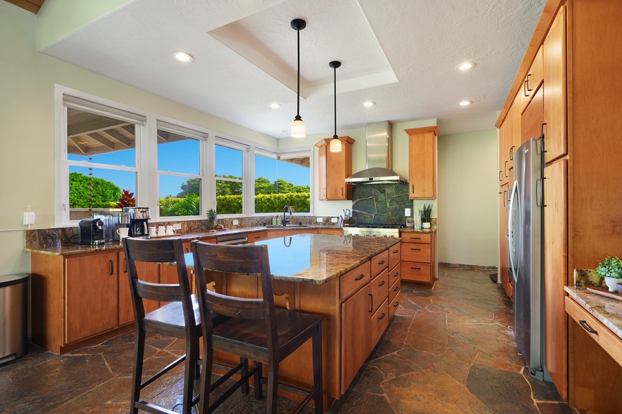 Your gourmet kitchen features granite countertops, modern appliances, and stunning tropical garden views through large windows for inspired cooking.