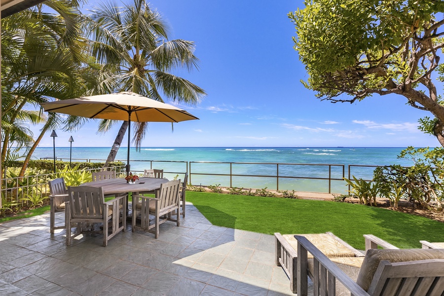 Oceanside lanai with lounge chairs and outdoor seating with umbrella.